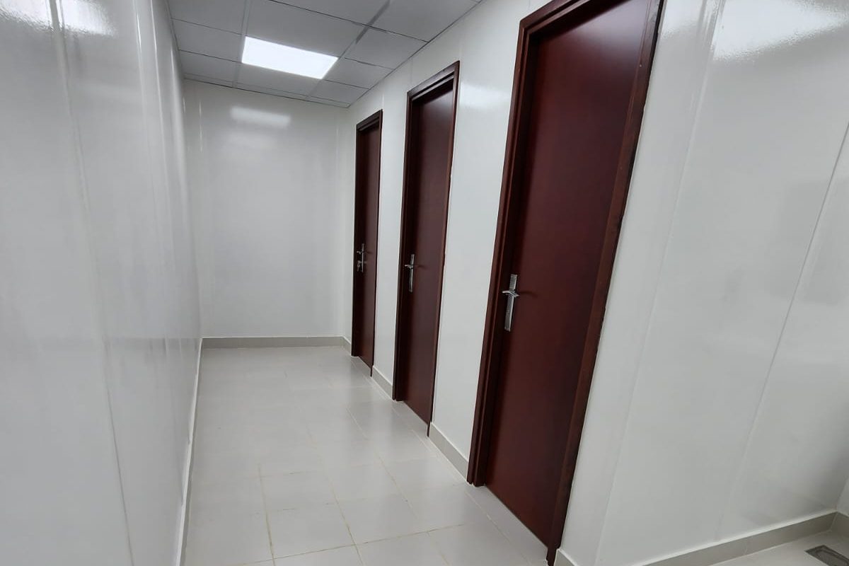 Washroom block, cubicle doors off the tiled corridor